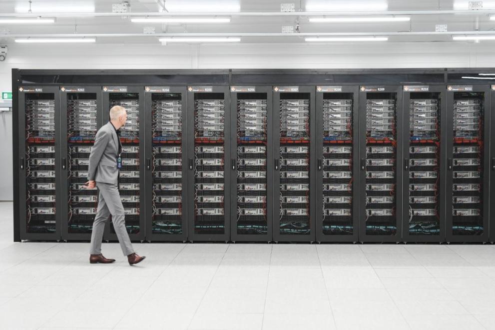 A man walks past a row of server racks at the LUMI supercomputer in Finland